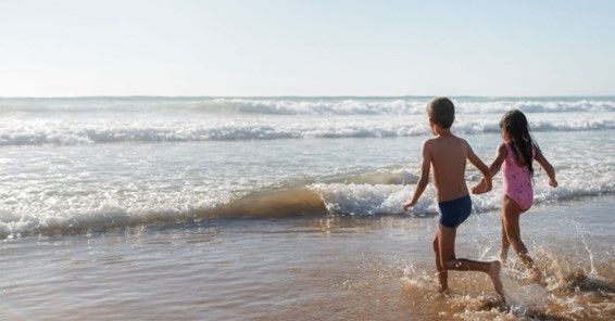 Kinder, die in der Bucht von Ibiza ins Meer rennen
